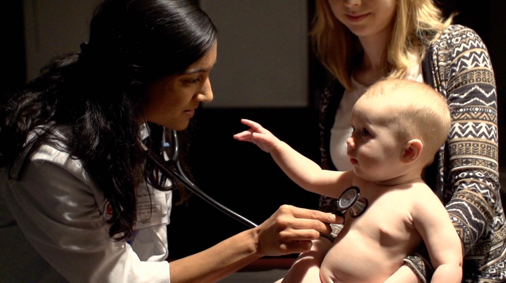 OU campaign still: a clinician caring for a baby with a parent present